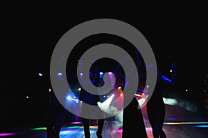 Silhouettes of dancing people in club in front of bright stage lights - disco concept.