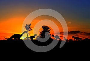 Silhouettes of dinosaurs in the forest on sunset background with copy space