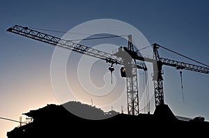 Silhouettes of elevating cranes