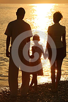Silhouettes of family against glossing sea photo