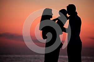 Silhouettes of family on hands against sea decline