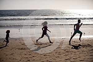 Silhouettes of family jogging along sea beach at sunrise. Outdoor workout, silhouettes of runners, sport and healthy