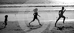 Silhouettes of family jogging along sea beach at sunrise. Outdoor workout, silhouettes of runners, sport and healthy