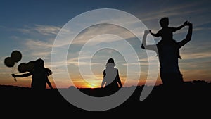 Silhouettes of family running in the meadow during sunset