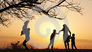 Silhouettes of family spending time together in the meadow near during sunset