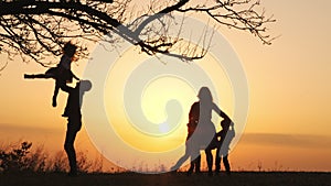 Silhouettes of family spending time together in the meadow near during sunset