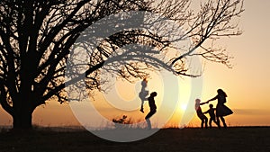 Silhouettes of family spending time together in the meadow near during sunset