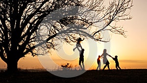 Silhouettes of family spending time together in the meadow near during sunset