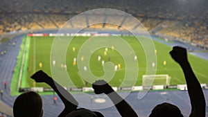 Silhouettes of fans hands in stadium while watching football match, cheering