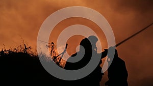 Silhouettes of firefighters extinguish fire