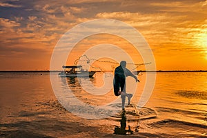 Silhouettes of the fishermen throwing fishing net during sunset in Dammam seaside Saudi Arabia