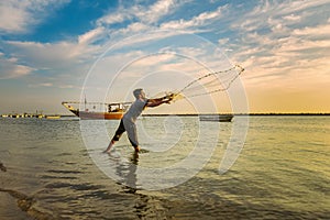 Silhouettes of the fishermen throwing fishing net during sunset in Dammam seaside Saudi Arabia
