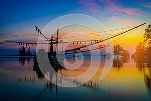 Silhouettes fishing boat and tree at sunset time