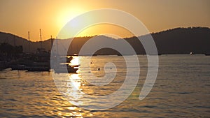 Silhouettes of fishing boats standing near seashore at sunset. Fisherman vessels swaying on waves in beautiful evening