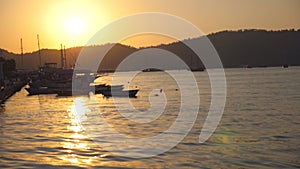 Silhouettes of fishing boats standing near seashore at sunset. Fisherman vessels swaying on waves in beautiful evening