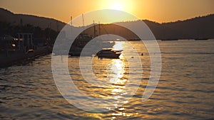 Silhouettes of fishing boats standing near seashore at sunset. Fisherman vessels swaying on waves in beautiful evening