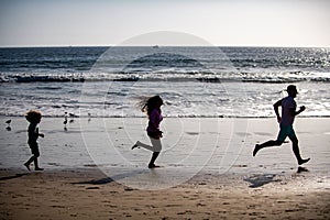 Silhouettes of fitness family running near sea. Family jogging for sport for fitness outdoors with child.