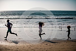 Silhouettes of fitness family running near sea. Family jogging for sport for fitness outdoors with child.