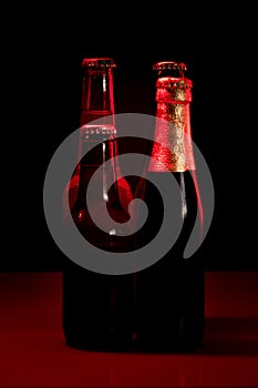 Silhouettes of four beer bottles on a black background and lit with red light