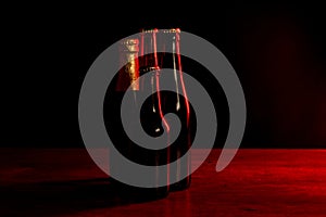 Silhouettes of four beer bottles on a black background with red lights that illuminate them on one side
