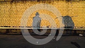 Silhouettes of girls dancing simultaneously against brick wall at sunset