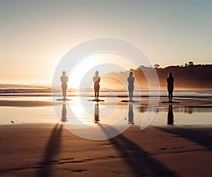 Silhouettes of girls doing yoga on the sand of a sunset beach with surf and sun