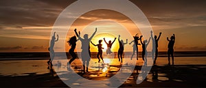 Silhouettes of a group of people on the beach, joyfully jumping up against the backdrop of the setting sun. The scene is