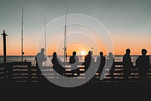 Silhouettes of a group of people on a pier, enjoying the beautiful sunset