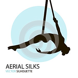 Silhouettes of a gymnast in the aerial silks