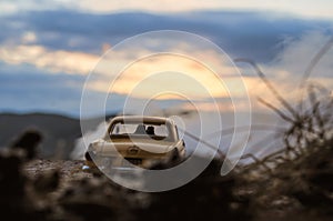 silhouettes of Happy Couple sitting in old vintage car at sunset time. Toy installation effect like reality. Selective focus