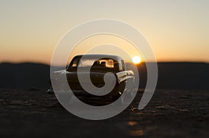 silhouettes of Happy Couple sitting in old vintage car at sunset time. Toy installation effect like reality. Selective focus
