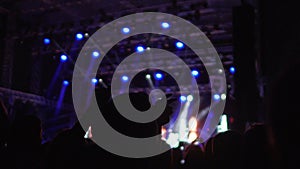 Silhouettes of happy people enjoying music at concert, waving hands in air