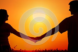 Silhouettes of happy smiling young couple in summer wheat field