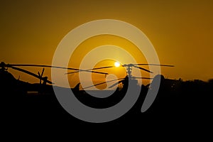 Silhouettes of Helicopters and Planes at the airport at Sunset