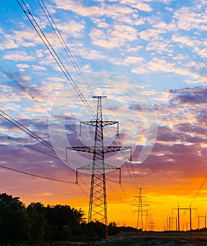 Silhouettes high voltage electric pylon in sunset background