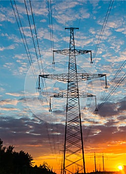 Silhouettes high voltage electric pylon in sunset background