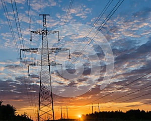 Silhouettes high voltage electric pylon in sunset background