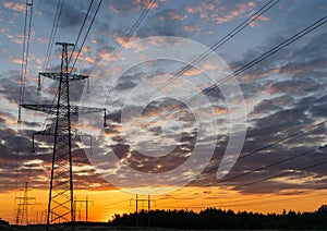 Silhouettes high voltage electric pylon in sunset background
