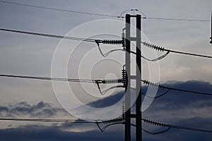 Silhouettes of high voltage lines in the sky background at sunset time