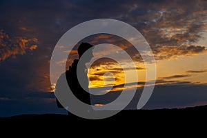 Silhouettes of hiker with backpack enjoying sunset view from top of a mountain