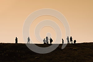 Silhouettes of hikers with backpacks enjoying sunset view from top of a mountain