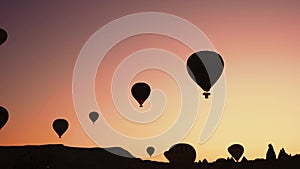 Silhouettes of hot air balloons over sunset background.