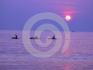 Silhouettes of kayakers in India sunset