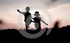 Silhouettes of kids jumping off a hill at sunset