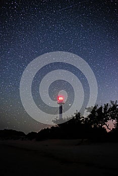 Silhouettes of the Lighthouse sandy beach and ocean against the background of the starry sky