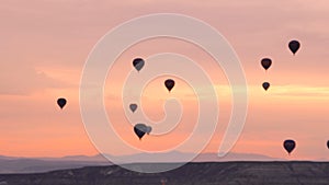 Silhouettes Lots of hot air balloons flying over valleys in Goreme, Turkey. Pink Dawn over the Incredible Place in