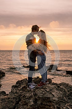 silhouettes in love romantic couple lovers hugging, kissing, touching, eye contact at sunset, sunrise on the background