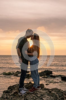 silhouettes in love romantic couple lovers hugging, kissing, touching, eye contact at sunset, sunrise on the background