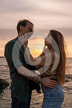 silhouettes in love romantic couple lovers hugging, kissing, touching, eye contact at sunset, sunrise on the background