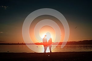 Silhouettes of a loving couple, beautiful sunset on a lake